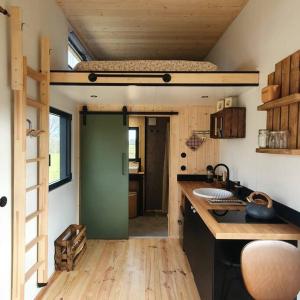 una cocina con una cama elevada en una casa pequeña en Tiny House nature proche Montargis - 1h de Paris ! 