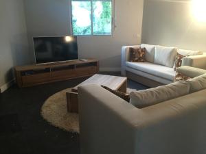 sala de estar con 2 sofás y TV de pantalla plana en Villa Luxe Mer & Piscine, en Sainte-Anne