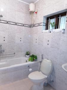 a bathroom with a toilet and a tub and a sink at Surendram Villa in Varkala