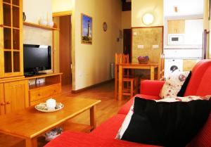 a living room with a red couch and a tv at Apartamentos Rurales La Fuente in Pesués