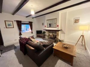- un salon avec un canapé en cuir et une cheminée dans l'établissement Scenic 2 bedroom Cottage, à Hill Top