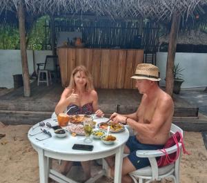 a man and woman sitting at a table eating food at Twice Happy Beach Garden in Tangalle