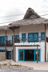 a building with a thatched roof and blue windows at Villa dos Poetas in Barra Grande