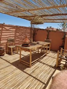 une terrasse en bois avec une table et des chaises sur un patio dans l'établissement maison noé , residence al quaria ab40, à Marrakech 15 autres photos