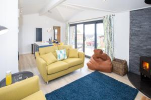 a living room with a yellow chair and a fireplace at Letham Feus Lodge and Caravan Park in Fife