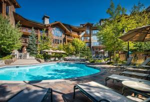 a pool at a resort with tables and chairs at First Tracks Lodge in Whistler