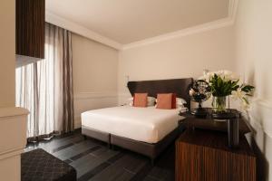 فندق بلازو نافونا في روما: غرفة نوم بسرير وطاولة مع ورد