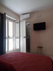 a bedroom with a bed and a flat screen tv at San Rocco Rooms in Palmi