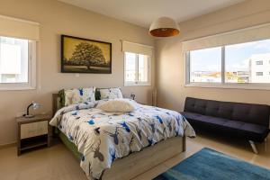 a bedroom with a bed and a couch and windows at Central Bliss / your perfect home away from home in Limassol