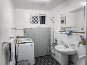 Elle comprend une petite salle de bains blanche pourvue d'un lavabo et de toilettes. dans l'établissement Newly renovated hidden gem, à Séoul