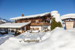 a building covered in snow with a pile of snow at Pension Rennlehen in Berchtesgaden
