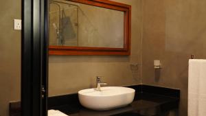 a bathroom with a white sink and a mirror at Woodgrove Cabanas in Negombo