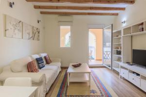 a living room with a white couch and a tv at Lodging Apartments Gracia in Barcelona