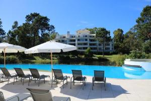 a pool with chairs and umbrellas in front of a building at Solanas Green park resort and spa Vacation Club in Punta del Este