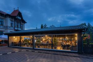 Hotel Carol - Vatra Dornei في فاترا دورني: مطعم به نوافذ زجاجية كبيرة والناس جالسين على الطاولات