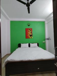 Un dormitorio con una pared verde y una cama en Ganga Putra Inn en Varanasi