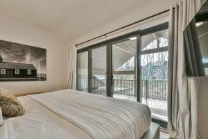 1 dormitorio con cama y ventana grande en 203 Verbier Building 7 - 5BR Tremblant Lux Condo Close to Everything, en Mont-Tremblant