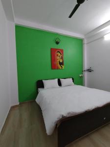 a bedroom with a green wall and a bed at Ganga Putra Inn in Varanasi