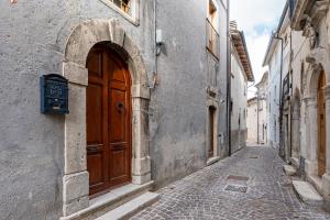un callejón con puerta de madera en un edificio en Casa Caniglia 34 - YourPlace Abruzzo, en Rivisondoli