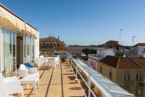 a balcony with white chairs and tables on a building at Villa Marquez in Vila Real de Santo António