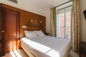 a bedroom with a white bed and a window at Villa Marquez in Vila Real de Santo António