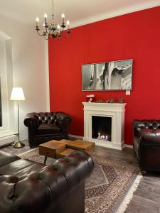 Waldhaus Pulsnitz في بولسنيتز: غرفة معيشة حمراء مع أثاث من الجلد ومدفأة