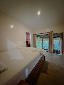 1 dormitorio con cama grande y ventana grande en Munduk Tutub waterfall view, en Munduk