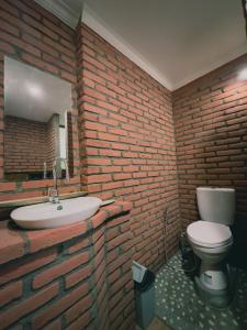 a brick bathroom with a sink and a toilet at Munduk Tutub waterfall view in Munduk