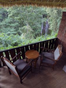 a balcony with a table and chairs and a waterfall at Munduk Tutub waterfall view in Munduk