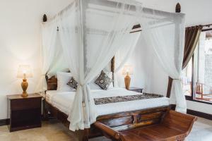 sypialnia z łóżkiem z baldachimem i białymi zasłonami w obiekcie Kishi-Kishi ArtVilla w mieście Blahbatu
