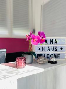 a table with a sign and flowers on it at Rooms & Glamping Lana Haus in Ličko Petrovo Selo