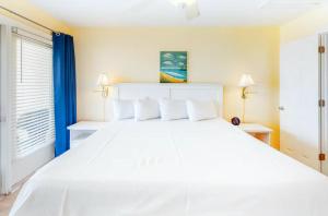 uma cama branca com almofadas brancas num quarto em Labacoco em Gulf Shores