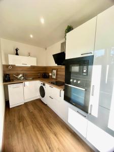 a kitchen with white cabinets and black appliances at Charmant studio + parking privé in Caen