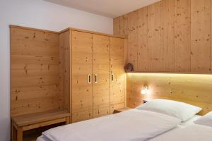 Schlafzimmer mit Holzwänden, einem Bett und Schränken in der Unterkunft Stoffel Apartments Marie in Selva