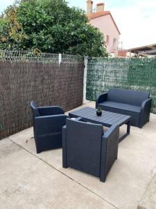 a patio with two chairs and a table and a fence at Joli appartement 3/4 personnes in Saleilles