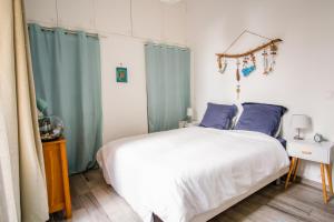 sypialnia z białym łóżkiem i niebieskimi zasłonami w obiekcie Appartement très cosy avec cour w Cannes