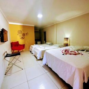 ExtremózにあるPOUSADA GENIPABU PRAIAのベッド2台と赤い椅子が備わるホテルルームです。