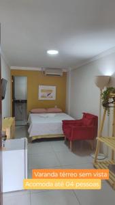 a bedroom with a bed and a red chair at POUSADA GENIPABU PRAIA in Extremóz