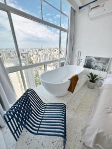 a bathroom with a white tub and a large window at Vem pro Copan in São Paulo