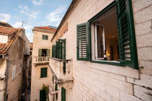 an alley with green shutters on a building at Slavija Culture Heritage Hotel in Split