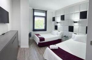 a hotel room with two beds and a television at Hoteles Urbanos N Avenida de España in Fuenlabrada