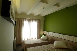 a green room with two beds and a window at Hotel La Fonda Moreno in Morella