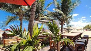 uma praia com mesas e cadeiras e palmeiras em POUSADA GENIPABU PRAIA em Extremóz