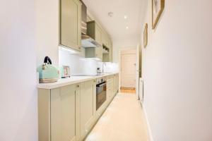 ロンドンにあるLittle Venice UK Bright & Stylish garden apartmentの白いキッチン(緑のキャビネット付)、廊下