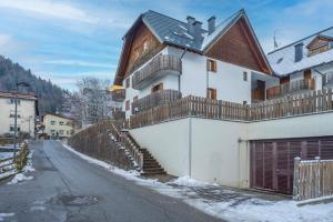 Casa blanca con una valla de madera y una calle nevada en Small & Charming Apt - Overlooking the Alps, en Tarvisio