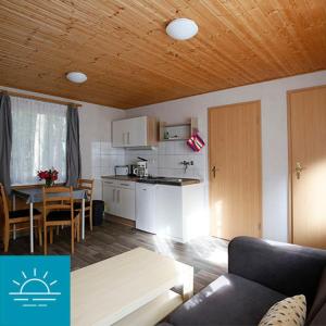 eine Küche und ein Wohnzimmer mit einem Tisch und einem Sofa in der Unterkunft Bungalow SONNE UND MEER direkt am Strand in Dranske