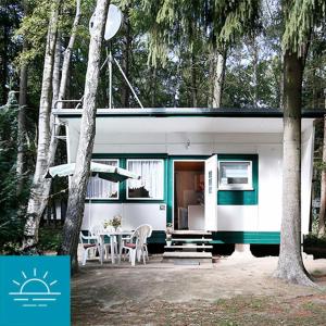 a green and white caravan with a table and chairs at Bungalow SONNE UND MEER direkt am Strand in Dranske