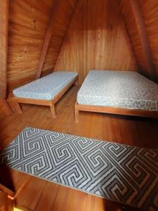 two beds in a sauna with wooden floors at Cabana com Ar condicionado e area de cozinha e banheiro compartilhado a 10 minutos do Parque Beto Carrero in Penha