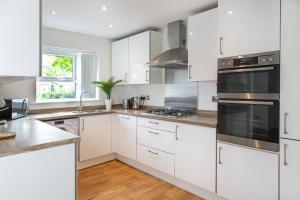 una cocina con armarios blancos y electrodomésticos de acero inoxidable en Cozy Townhouse in the heart of Greater Manchester en Mánchester