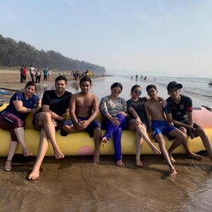 a group of people sitting on a surfboard on the beach at SAMARA SEAVIEW in Alibag